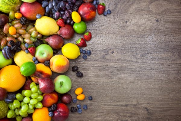 Different Organic Fruits with water drops on wooden table back